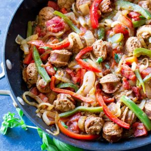 sliced sausage, green and red bell peppers and onions in a pan