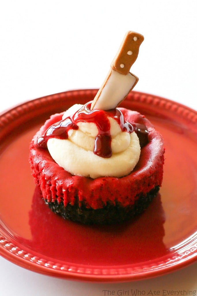 Mini Red Velvet Cheesecakes - moist red velvet cheesecake with an Oreo crust. The best recipe I've ever had. Topped with cream cheese for the ultimate indulgence. Add some edible blood for a dramatic Halloween dessert. the-girl-who-ate-everything.com