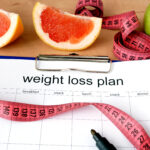 Paper with weight loss plan and grapefruit