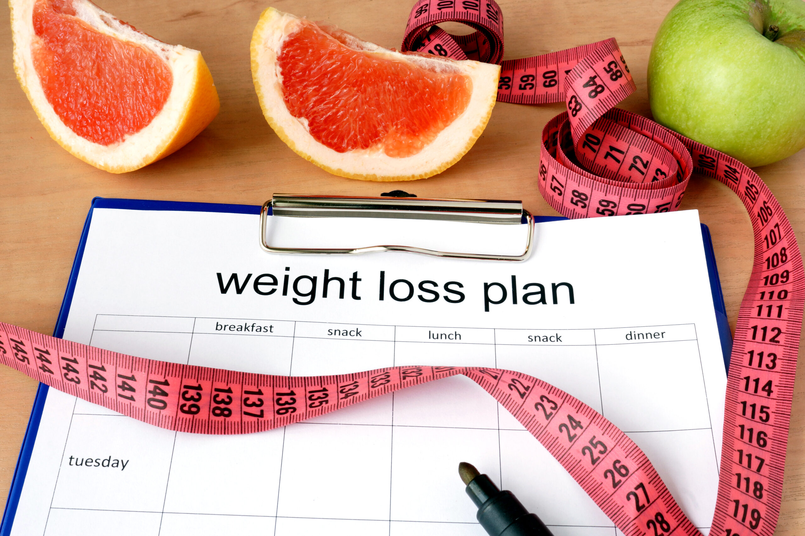 Paper with weight loss plan and grapefruit