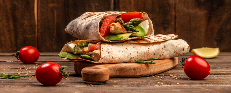 Tortilla wrap with asparagus, cherry tomatoes, avocado, chicken fillet and fresh salad. healthy food. Top view. Long banner format. space for text.