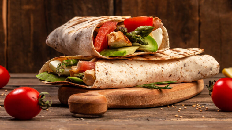 Tortilla wrap with asparagus, cherry tomatoes, avocado, chicken fillet and fresh salad. healthy food. Top view. Long banner format. space for text.