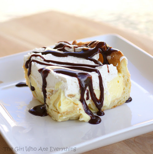 This Chocolate Eclair Cake has a cream puff crust, vanilla cream cheese layer, whipped cream, and a chocolate drizzle. It's all the flavors of an eclair in cake form. the-girl-who-ate-everything.com