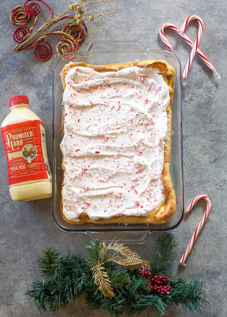 This Eggnog Éclair Cake is a unique holiday dessert with a cream puff crust, creamy eggnog layer, and topped with fresh cream and crushed peppermint candies.